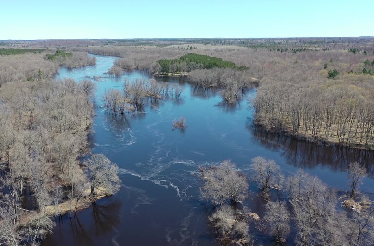 Aerial perspective of Michigan’s Upper Peninsula landscape known as Anaem Omot, including Sixty Islands and ancestral Menominee sites, captured in early May before leaf emergence.