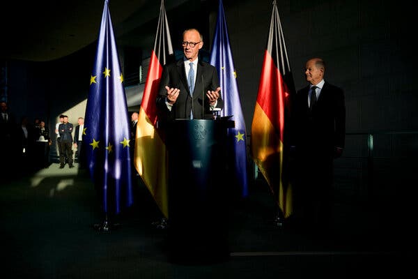 Friedrich Merz, newly appointed German chancellor, attends a ceremony in Berlin on Tuesday with former Chancellor Olaf Scholz observing.