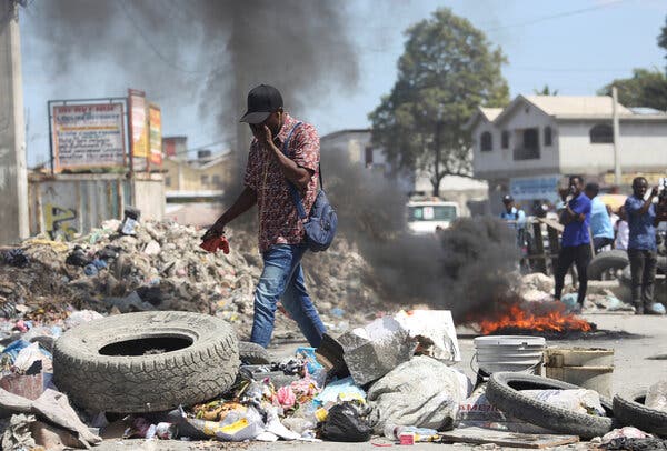 A man passes a flaming barricade set up to protest the lack of security in Tabarre neighborhood, Port-au-Prince, in February.