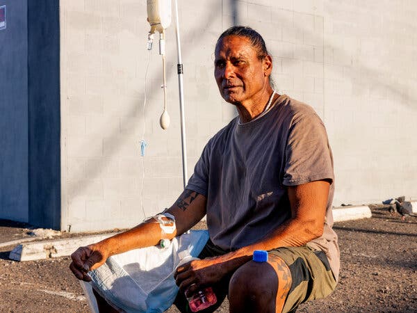 Hawaii Kalawaia is treated with IV fluids in a Phoenix parking lot, confronting the challenge of enduring the city’s intensifying summer heat while homeless.