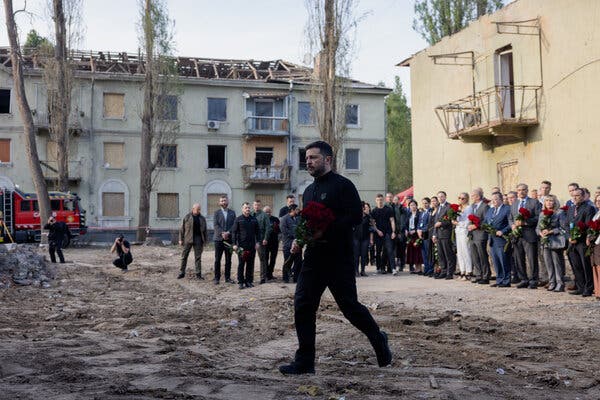 Ukrainian President Volodymyr Zelensky lays flowers at a residential building in Kyiv hit by a Russian missile strike on Friday.