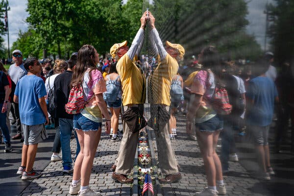 Sam Calabrese, a National Park Service volunteer, assists a visitor in locating a name on the Vietnam Veterans Memorial during the 50th anniversary of Saigon’s fall.