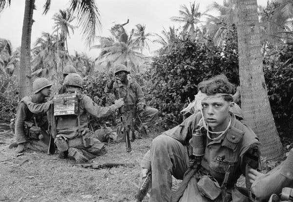 American troops take cover along a tree line under fire in Vietnam, March 1967. The war’s impact has lingered with many veterans for decades.